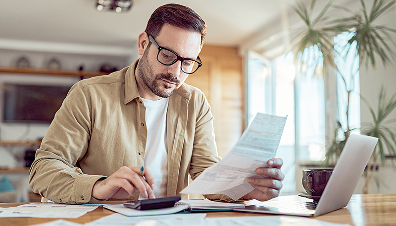 Young man working on his financial bills at home.