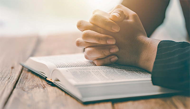 Cropped view of young woman praying with bible on table Confession concept Pray and talk with God