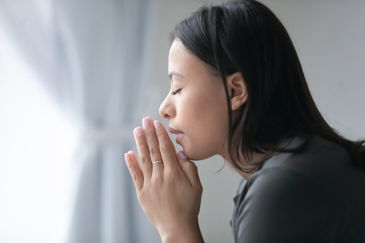 Religious biracial woman pray to God at home