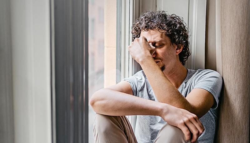 Depressed Young Man Sitting By The Window