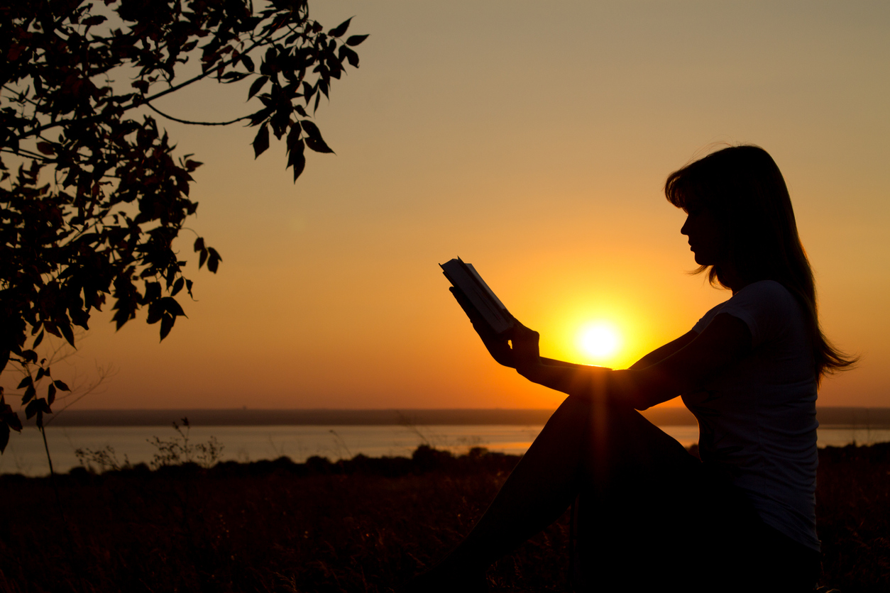 silhouette of  girl with a book in hands at sunset