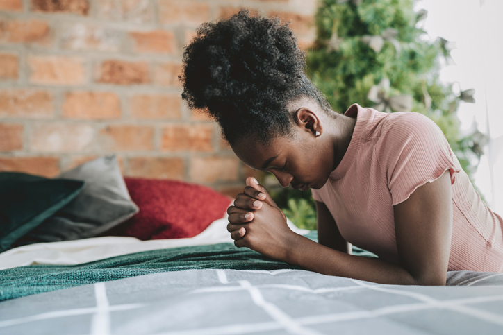 Child kneeling praying in the room