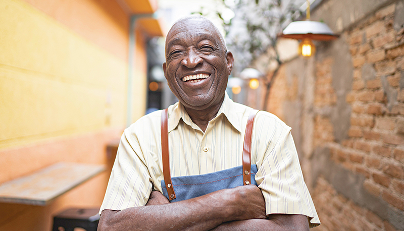 Portrait of smiling elderly waiter looking at camera